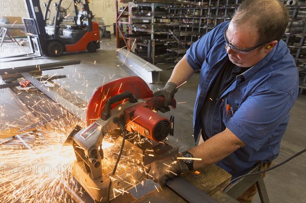 Caucasian worker cutting metal in factory