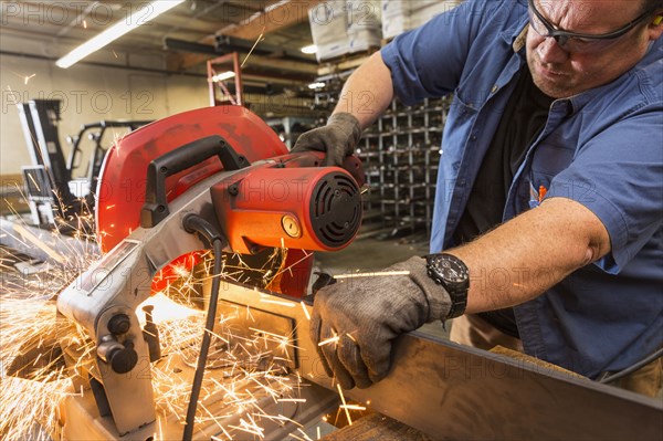 Caucasian worker cutting metal in factory