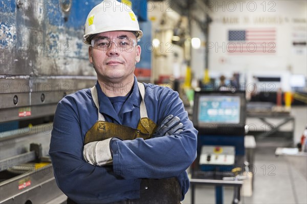 Serious Hispanic worker posing in factory