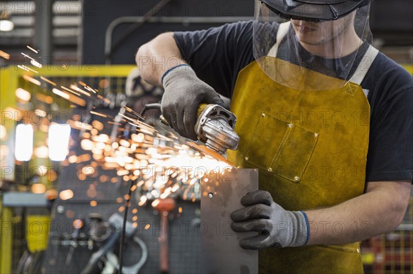 Caucasian worker grinding metal in factory