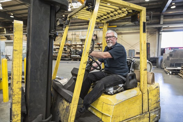 Caucasian worker driving forklift in factory