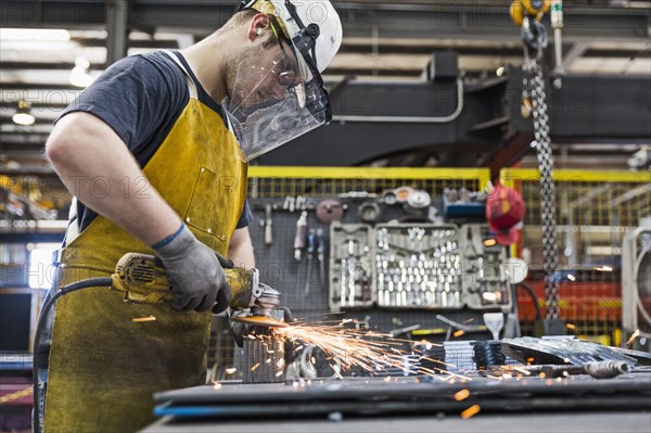 Caucasian worker grinding metal in factory