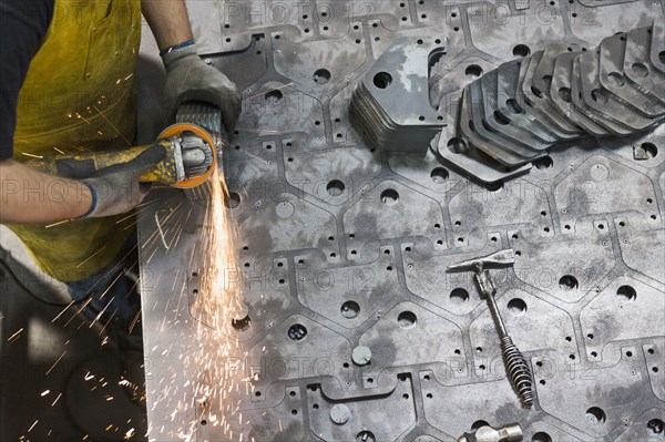 Caucasian worker grinding metal in factory