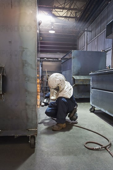 Caucasian worker grinding metal container in factory