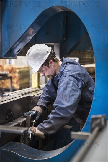 Caucasian worker fabricating metal in factory