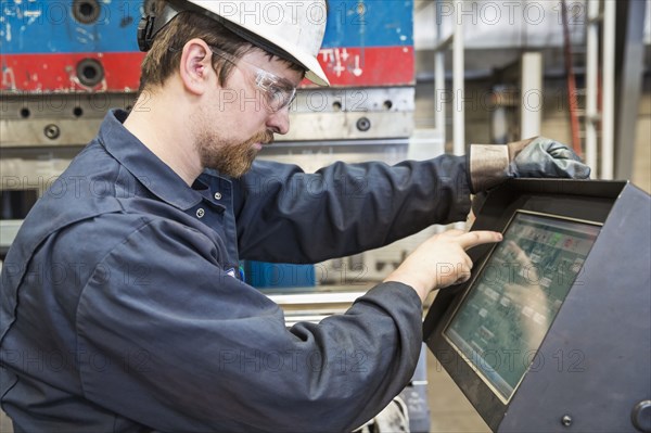 Caucasian worker using control panel in factory