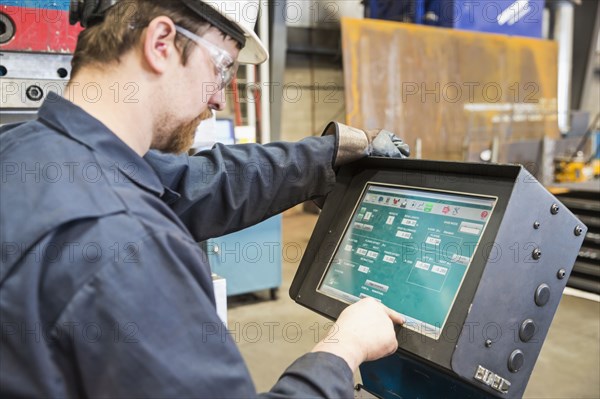 Caucasian worker using control panel in factory