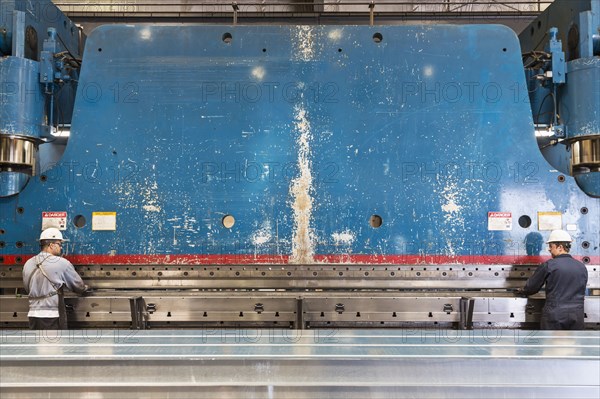 Workers fabricating metal in factory