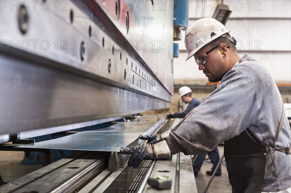 Workers fabricating metal in factory