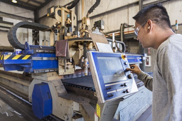 Asian worker using control panel in factory