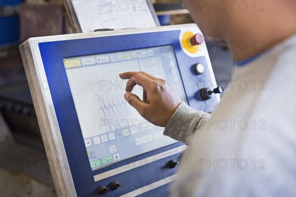 Asian worker using control panel in factory