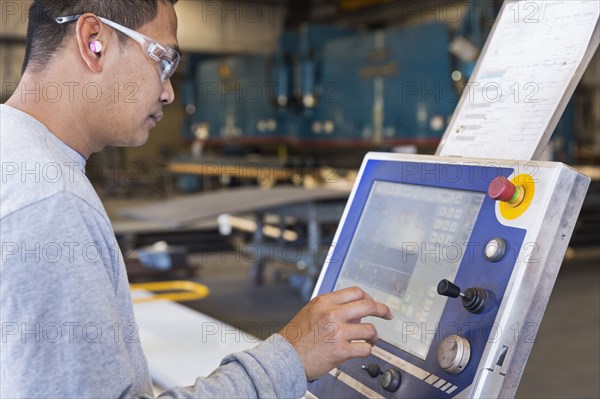 Asian worker using control panel in factory