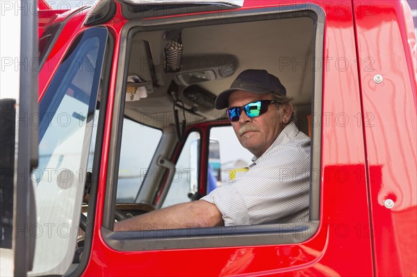 Serious Caucasian semi-truck driver wearing sunglasses