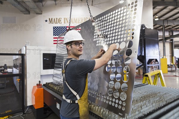 Caucasian worker fabricating metal in factory