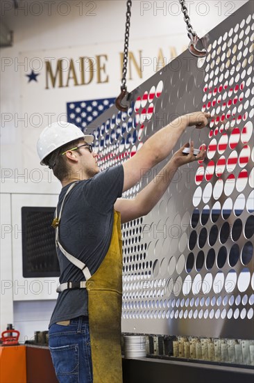 Caucasian worker fabricating metal in factory