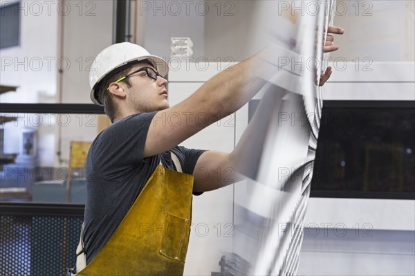 Caucasian worker fabricating metal in factory