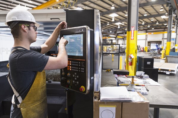 Caucasian worker using control panel in factory