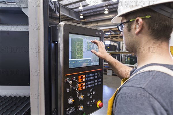 Caucasian worker using control panel in factory