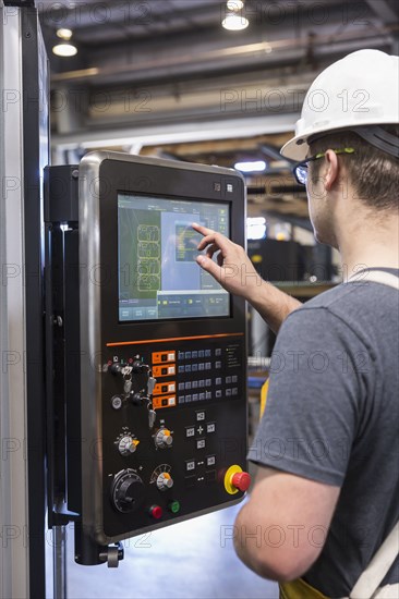 Caucasian worker using control panel in factory