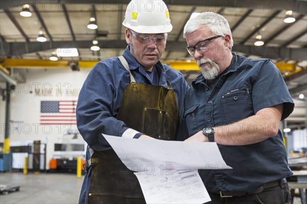 Workers reading paperwork in factory