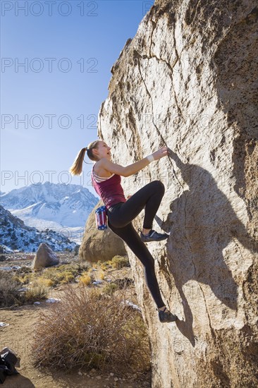 Caucasian teenage girl climbing rock