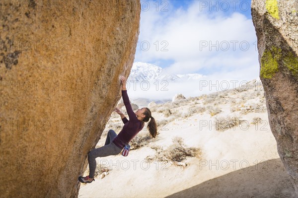 Mixed Race girl climbing rock