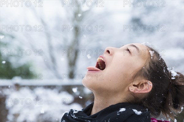 Mixed Race girl catching snowflakes on tongue