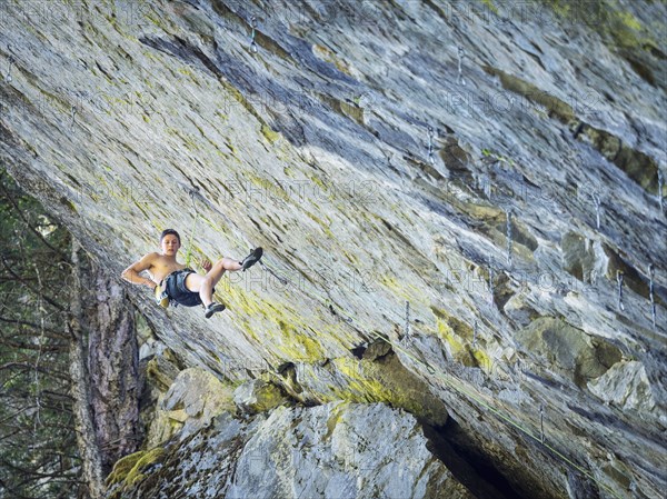 Caucasian boy hanging from rope on rock