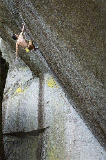 Mixed race boy rock climbing