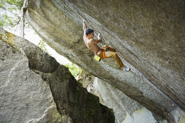 Mixed race boy rock climbing