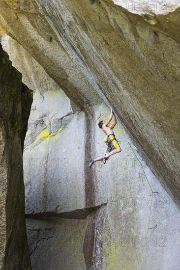 Mixed race boy hanging from rock