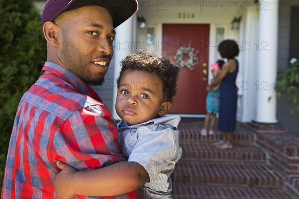 Smiling mixed race father carrying baby son