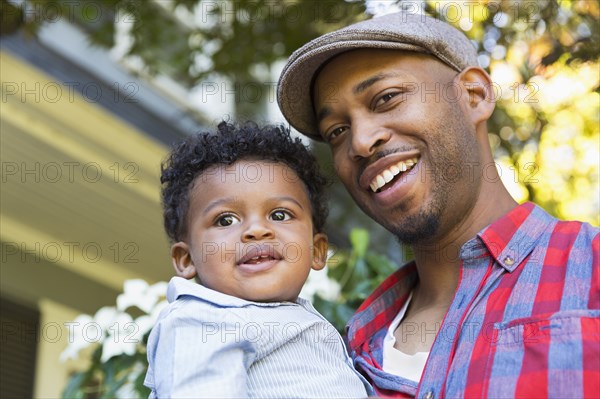 Smiling mixed race father holding baby son