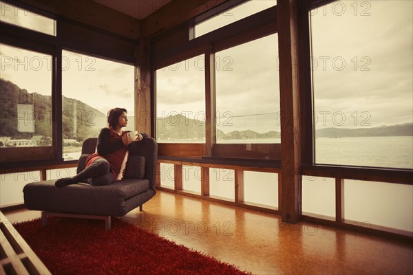 Mixed race woman looking out window of modern house