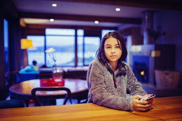 Mixed race girl using cell phone at table