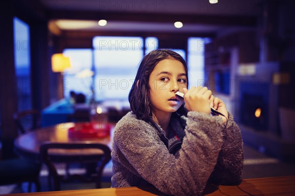 Mixed race girl holding cell phone at table