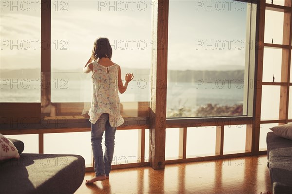 Mixed race girl looking out living room window