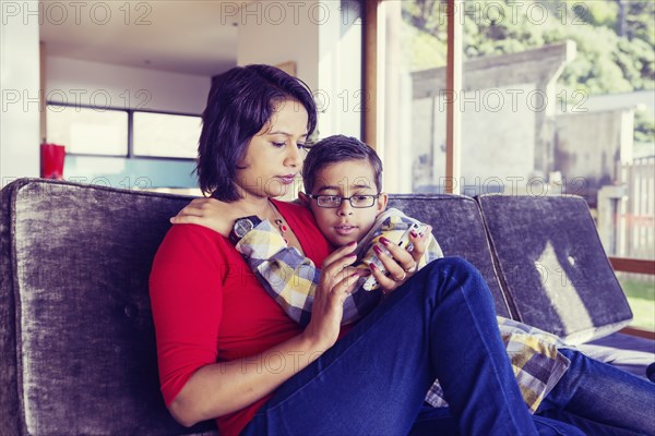 Mother and son using cell phone in living room