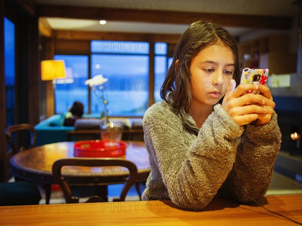 Mixed race girl using cell phone at table