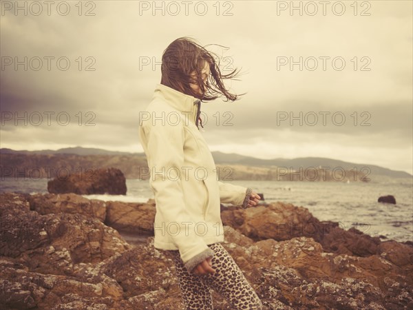 Mixed race girl walking on rocky beach