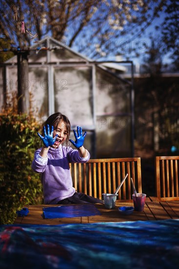 Mixed race girl finger painting on wooden deck