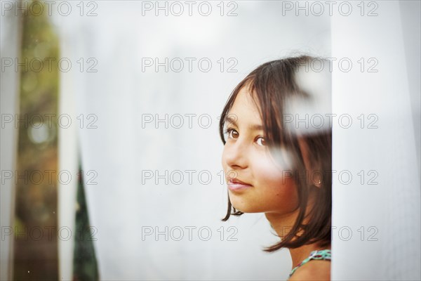 Mixed race girl standing near window