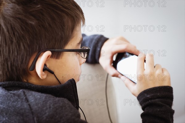 Mixed race boy listening to earbuds and using cell phone