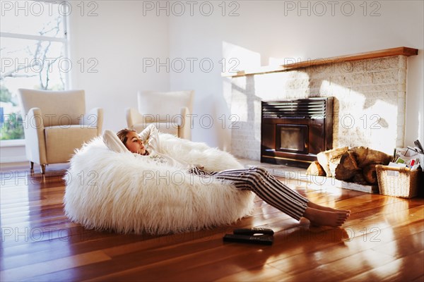 Mixed race girl relaxing in beanbag chair in living room