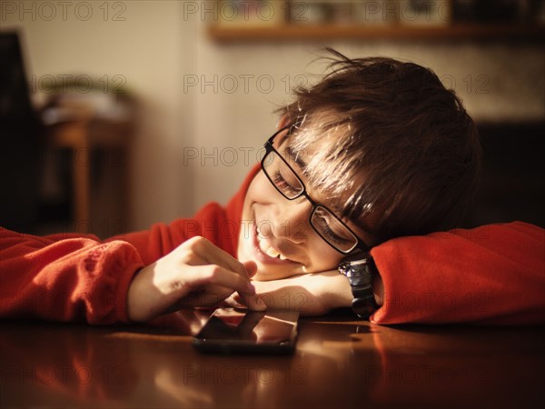 Mixed race boy using cell phone at table