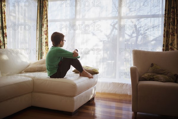 Mixed race girl looking out living room window