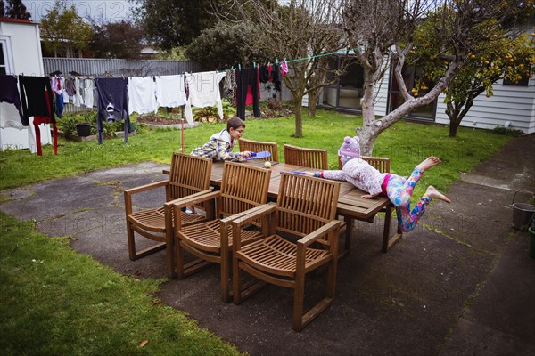 Mixed race brother and sister playing at table in backyard