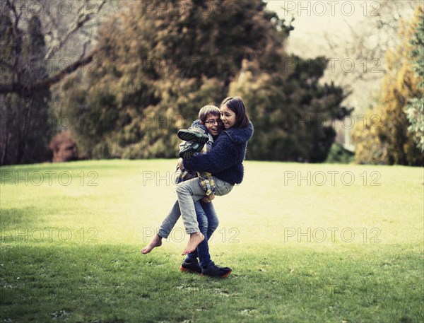 Mixed race brother and sister playing in field