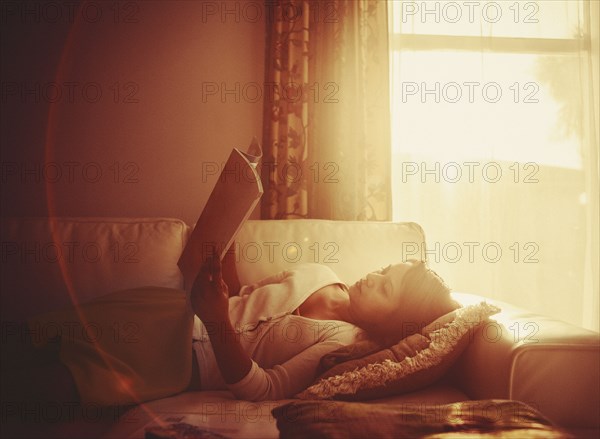 Mixed race woman using digital tablet on living room sofa