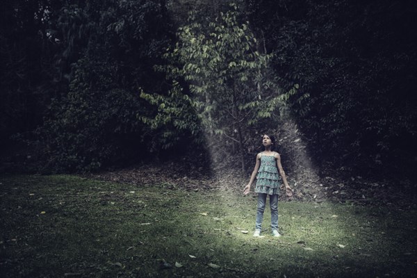 Mixed race girl standing in beam of light outdoors